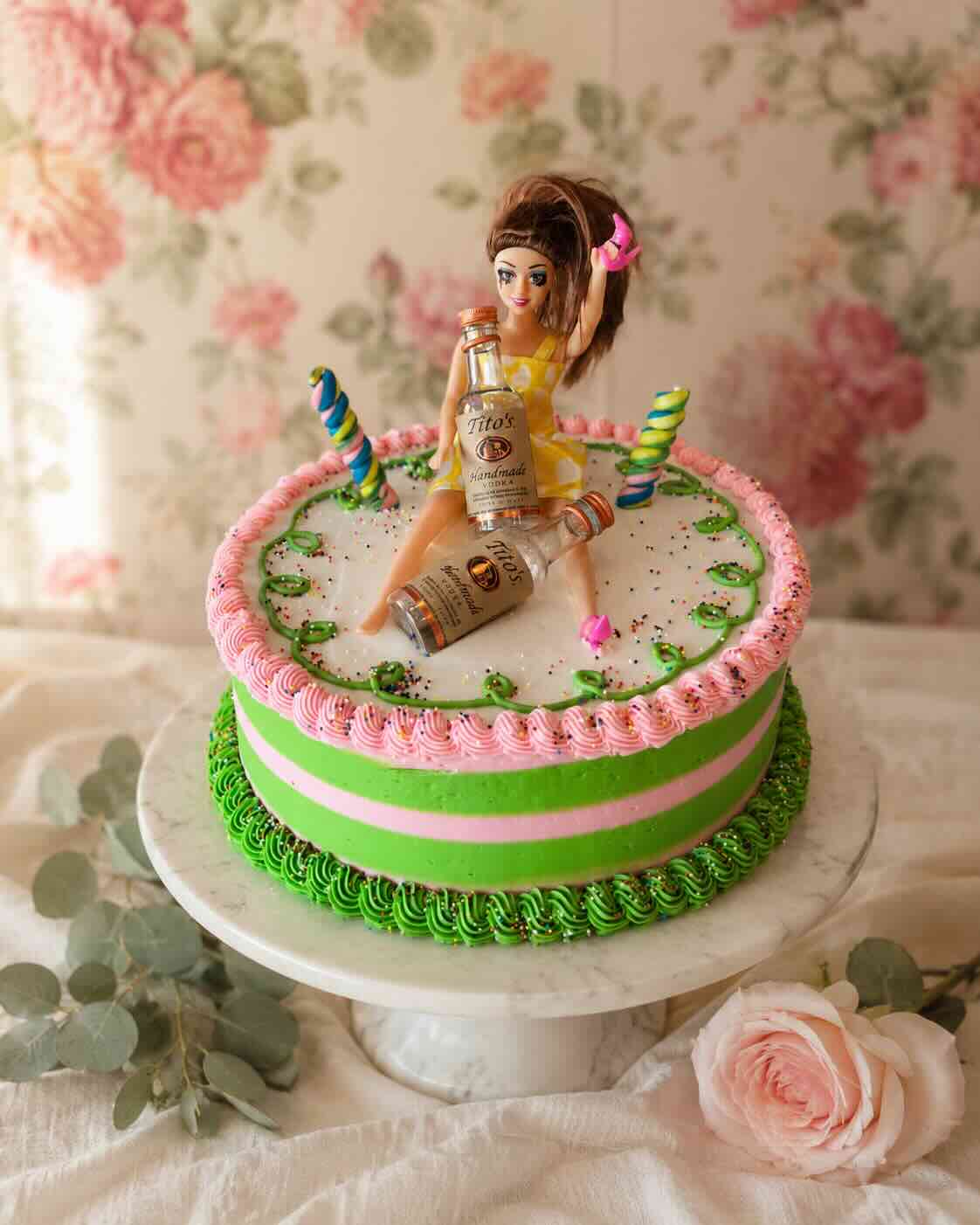 Pink and green striped bachelorette cake with a playful doll topper on a marble stand, Scottsdale