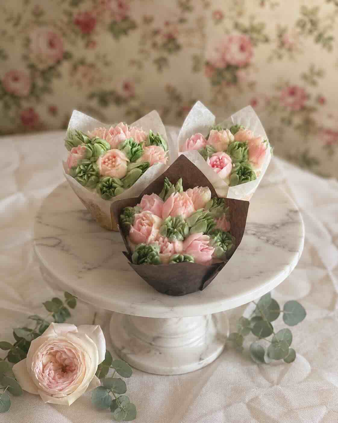 Buttercream flower cupcakes piped as pink roses and greenery on a marble stand, SweetScape Bakery in Scottsdale