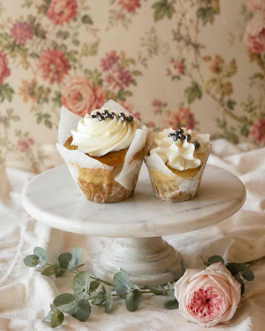 Vanilla cupcakes with swirled vanilla buttercream and pearl sprinkles on a marble stand, SweetScape Bakery in Scottsdale